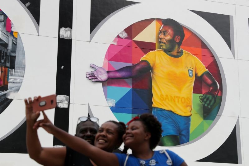People take a selfie near a mural depicting Brazilian soccer legend Pele in Santos, Brazil October 20, 2020. REUTERS/Amanda Perobelli