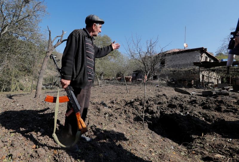 Local resident Alexei Agadzhanov holds a rifle while showing a crater following recent shelling in the settlement of Shosh in the course of a military conflict over the breakaway region of Nagorno-Karabakh, October 17, 2020. (REUTERS Photo)