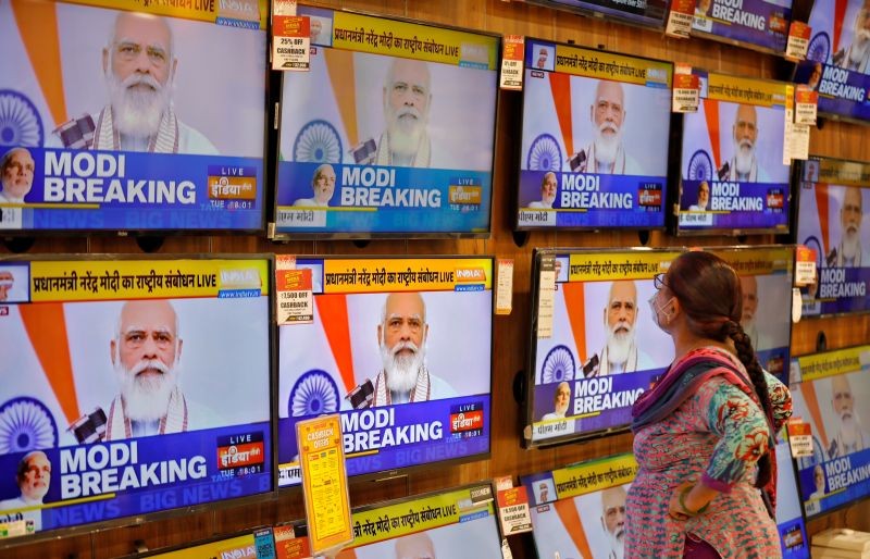 A woman wearing a protective mask watches Indian Prime Minister Narendra Modi on TV screens inside a showroom, amidst the spread of the coronavirus disease (COVID-19), in Ahmedabad, India, October 20, 2020. REUTERS/Amit Dave
