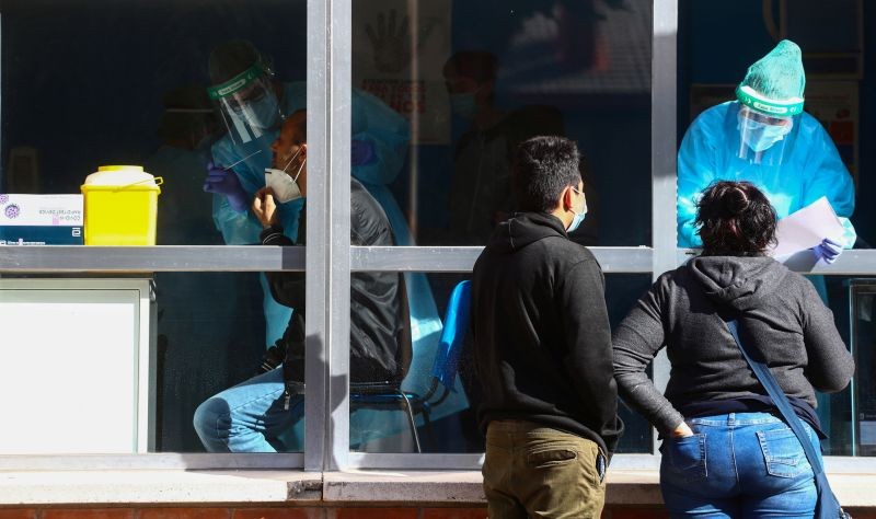 A health worker gives antigen results to a couple as another takes a swab sample for a coronavirus disease (COVID-19) antigen test inside a primary health centre at the working-class neighbourhood of Orcasitas, which has been under partial lockdown, amid the coronavirus disease (COVID-19) outbreak in Madrid, Spain, September 30, 2020. (REUTERS Photo)