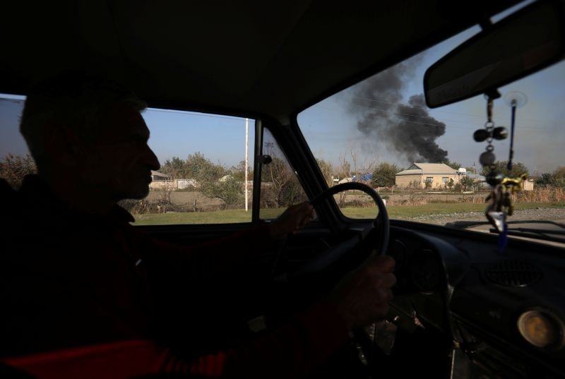 A man drives a car as smoke rises over the buildings during the fighting over the breakaway region of Nagorno-Karabakh, in the city of Terter, Azerbaijan October 19, 2020. (REUTERS Photo)