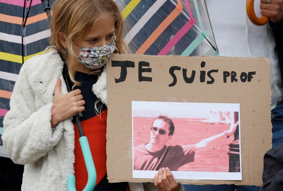 People gather at the Place de la Republique in Paris, to pay tribute to Samuel Paty, the French teacher who was beheaded on the streets of the Paris suburb of Conflans-Sainte-Honorine, France, October 18, 2020. REUTERS/Charles Platiau