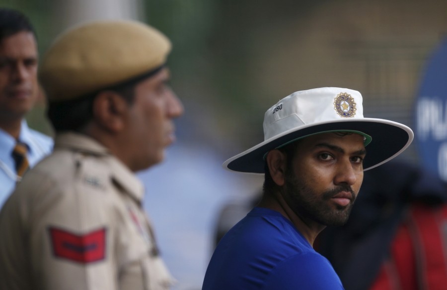 FILE PHOTO: Rohit Sharma watches his teammates practicing in the nets as a policeman stands guard during a practice session ahead of their first test cricket match against South Africa, in Mohali, India, November 4, 2015. REUTERS/Adnan Abidi