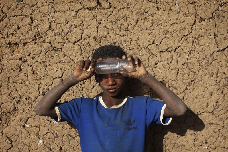 Local resident Soumaila Dicko, 9, shades his eyes from the sun with an empty plastic bottle in front of a mud brick house in Gao February 25, 2013. (REUTERS File Photo)