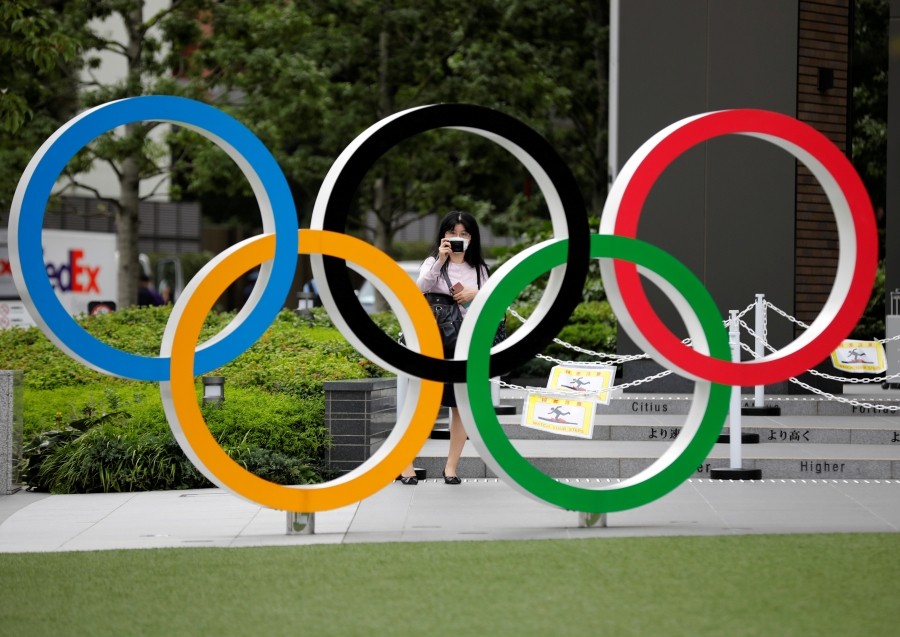 FILE PHOTO: A woman wearing a protective mask amid the coronavirus disease (COVID-19) outbreak, takes a picture of the Olympic rings in front of the National Stadium in Tokyo, Japan October 14, 2020. REUTERS/Kim Kyung-Hoon/File Photo