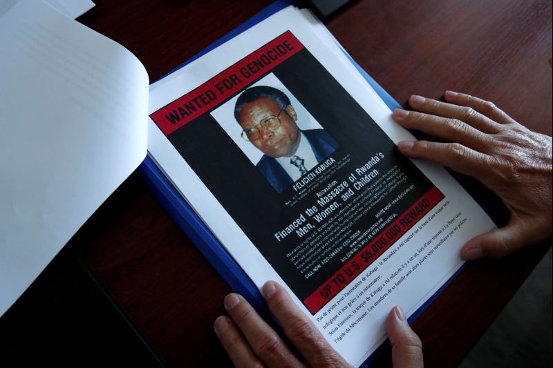 Eric Emeraux, head of the Gendarmerie's Central Office for Combating Crimes Against Humanity, Genocides and War Crimes (OCLCH), displays documents with a wanted poster depicting a photograph of Felicien Kabuga during an interview with Reuters at his office, about the arrest of Rwandan genocide fugitive suspect Felicien Kabuga, in Paris, France, May 19, 2020. (REUTERS File Photo)
