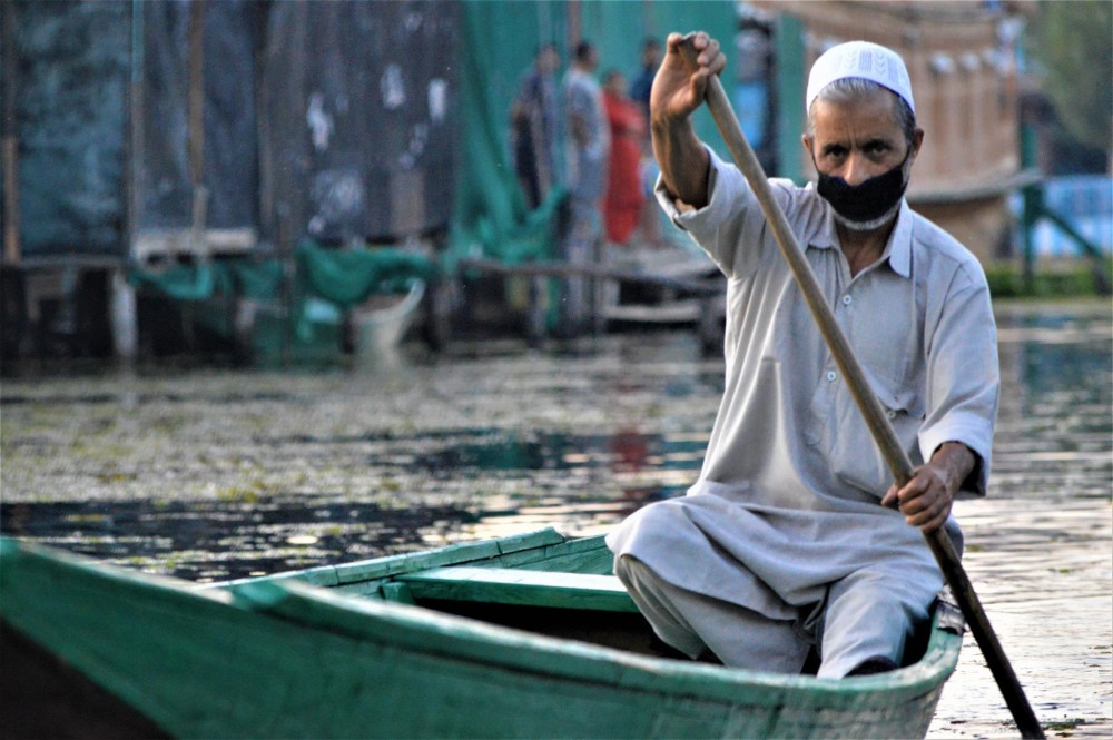 A man rows his boat on Dal Lake in Srinagar, Kashmir, India, September 12, 2020. Thomson Reuters Foundation/Athar Parvaiz