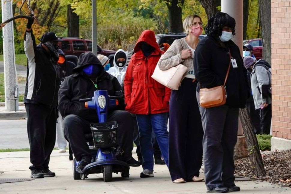 People wearing protective masks queue to enter a polling site at the Milwaukee Public Library?s Washington Park location in Milwaukee, on the first day of in-person voting in Wisconsin, U.S., October 20, 2020. REUTERS/Bing GuanREUTERS