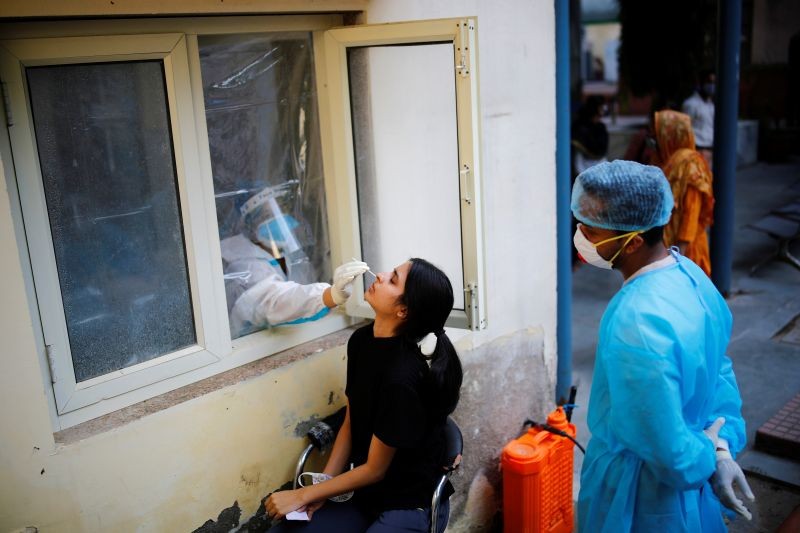 A health worker in personal protective equipment (PPE) collects a sample using a swab from a person at a local health centre to conduct tests for the coronavirus disease (COVID-19), amid the spread of the disease, in New Delhi, India October 7, 2020. REUTERS/Adnan Abidi/Files