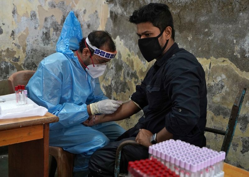 A healthcare worker wearing a protective gear collects blood sample from a man, who has recovered from the coronavirus disease (COVID-19), during a plasma donation camp inside a classroom at a slum in Mumbai on July 24, 2020.  (REUTERS File Photo)