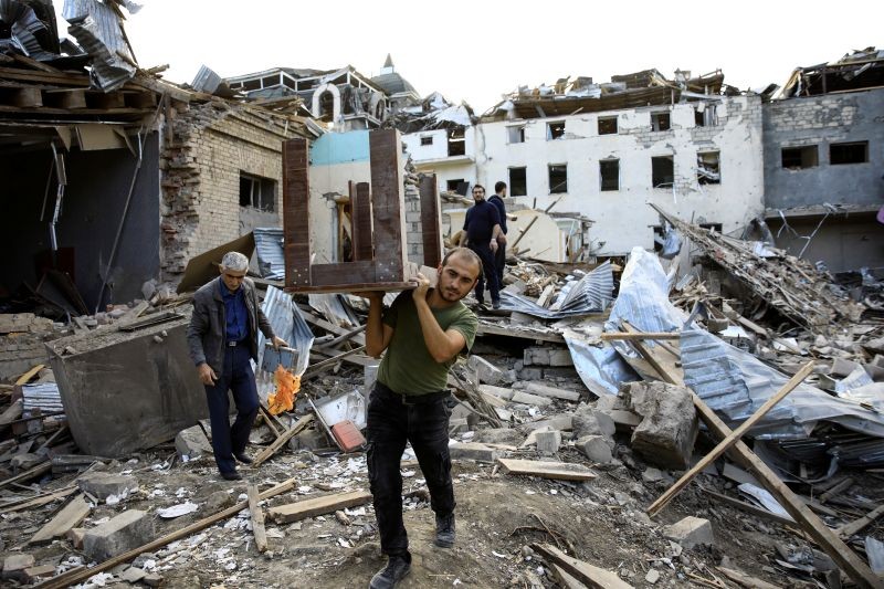 A man carries a table away from ruins at a blast site hit by a rocket during the fighting over the breakaway region of Nagorno-Karabakh in the city of Ganja, Azerbaijan October 11, 2020. REUTERS/Umit Bektas