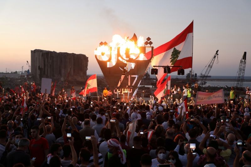 Anti-government demonstrators take pictures of a metal sculpture spelling out the word "revolution" topped by flames during a protest as Lebanese mark one year since the start of nation-wide protests, near Beirut's port, Lebanon October 17, 2020. REUTERS/Mohamed Azakir