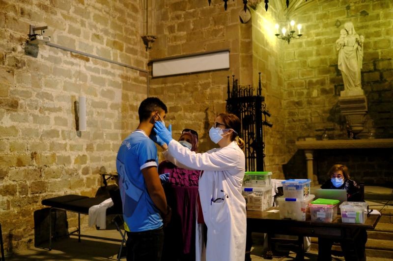 A man receives medical treatment by Merce Lopez, 42, who is a a volunteer doctor doing health checks for people amid economic hardship inside of Parish Church of Santa Anna, after Catalonia's government imposed new restrictions in an effort to control the spread of the coronavirus disease (COVID-19), in Barcelona, Spain October 29, 2020. (REUTERS Photo)