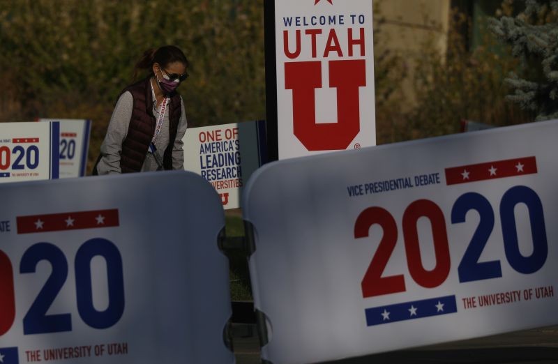 A woman walks past signs, a day ahead of the vice presidential debate between Republican vice presidential nominee and U.S. Vice President Mike Pence and Democratic vice presidential nominee and U.S. Senator Kamala Harris, on the campus of the University of Utah in Salt Lake City, Utah, US on October 6, 2020. (REUTERS Photo)