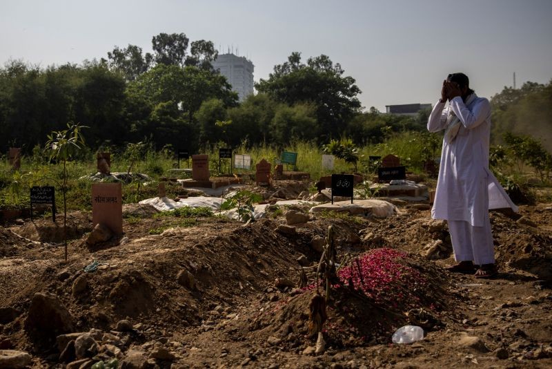 A man prays next to the grave of his relative, who died from the coronavirus disease (COVID-19), at a graveyard in New Delhi on October 6. (REUTERS Photo)