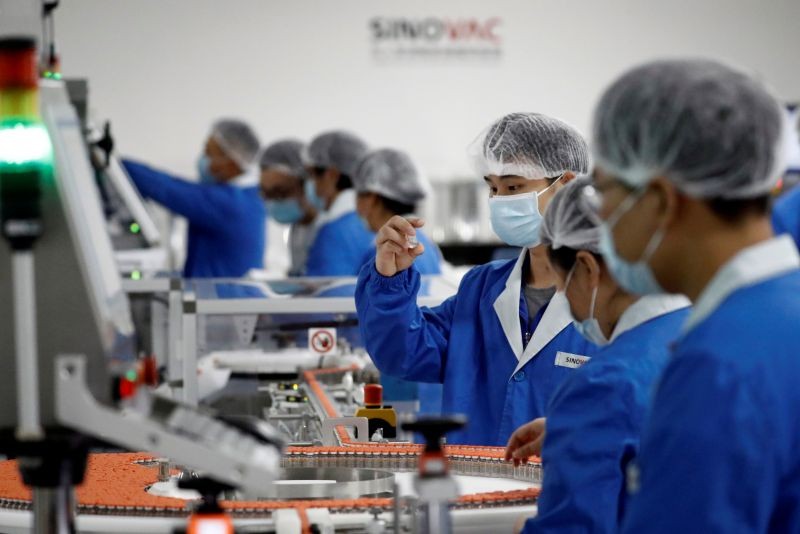 FILE PHOTO: People work in the packaging facility of Chinese vaccine maker Sinovac Biotech, developing an experimental coronavirus disease (COVID-19) vaccine, during a government-organized media tour in Beijing, China, September 24, 2020. REUTERS/Thomas Peter/File Photo