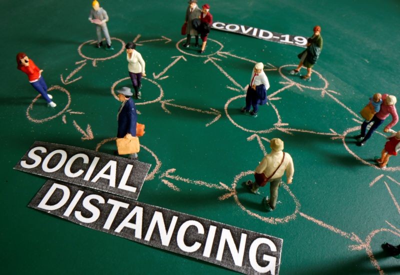 Small toy figures are placed on a chalkboard near "Social distancing - COVID-19" words printed on paper in this illustration taken May 27, 2020. (REUTERS File Photo)