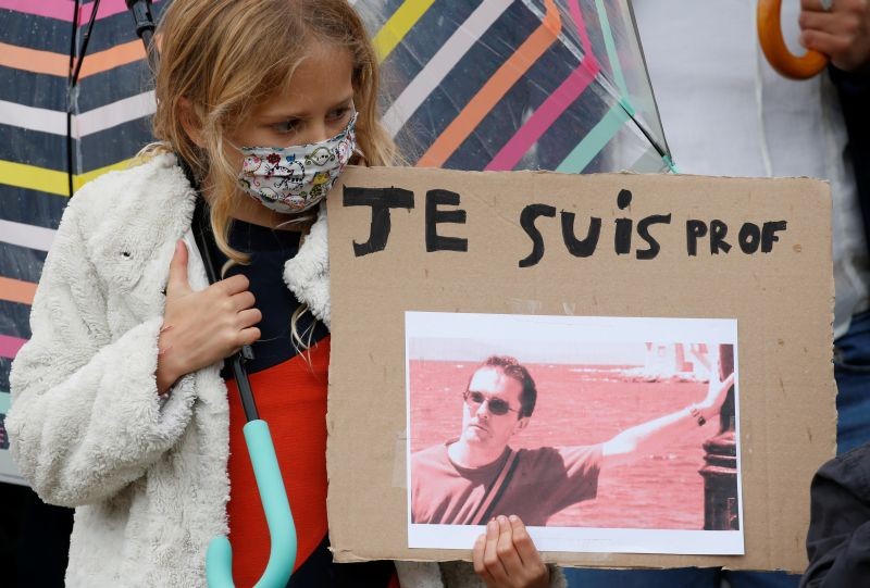 A girl holds a banner with a picture of Samuel Paty, the French teacher who was beheaded on the streets of the Paris suburb of Conflans St Honorine, during a tribute at the Place de la Republique, in Lille, France, October 18, 2020. (REUTERS Photo)