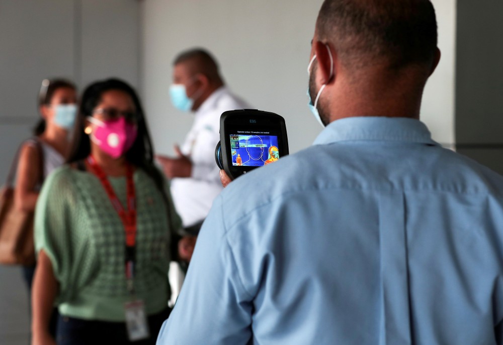 FILE PHOTO: An employee measures the temperatures of travelers at the Tocumen International Airport during the coronavirus disease (COVID-19) outbreak, in Panama City, Panama October 16, 2020. REUTERS/Erick Marciscano