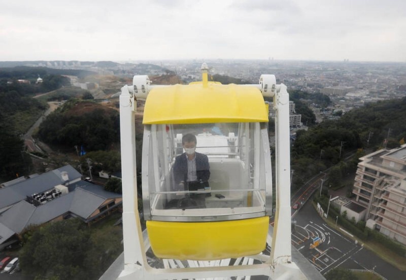A man uses a laptop on a Ferries wheel at 'Amusement Workation' which lets teleworkers work from a Ferris wheel and pool side amid the coronavirus disease (COVID-19) outbreak, at Yomiuriland in Tokyo, Japan October 15, 2020. (Reuters File Photo)