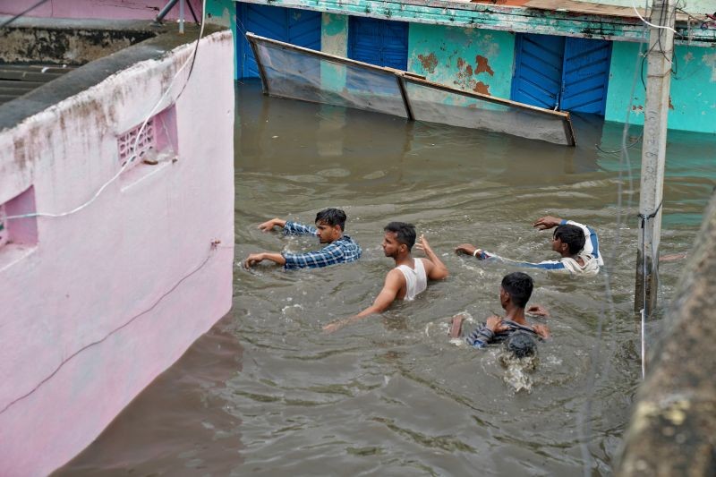 Residents wade through a waterlogged alley after heavy rainfall in Hyderabad, the capital of the southern state of Telangana on October 14. (Reuters Photo)