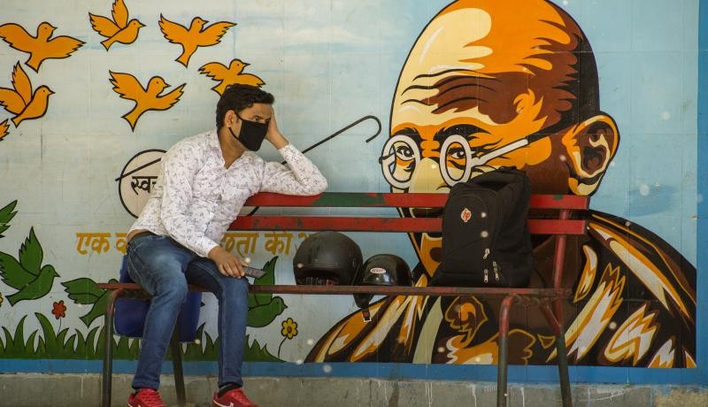 An Indian man wearing a protective mask sits on a bench, as India remains under an unprecedented lockdown over the highly contagious coronavirus (COVID-19) in New Delhi, India. Photo by Yawar Nazir/Getty Images.