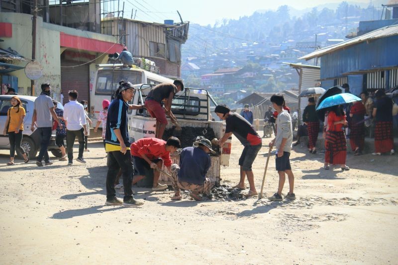Members of The Gigglers and United Labours Society filling up a pothole with gravel and soil at High School Junction, Tuensang town on November 7. (Morung Photo)