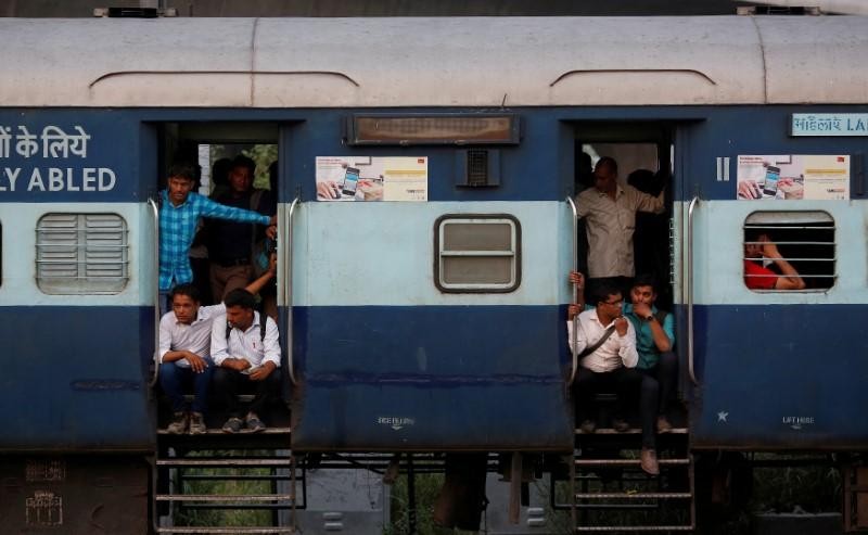 FILE PHOTO: Commuters sit on the doorstep of a moving train in New Delhi, June 16, 2017. REUTERS/Adnan Abidi/File Photo