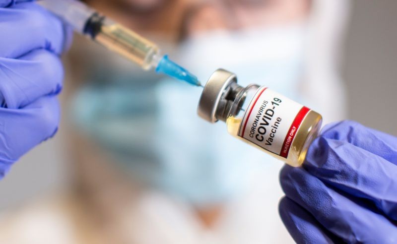 A woman holds a small bottle labeled with a "Coronavirus COVID-19 Vaccine" sticker and a medical syringe in this illustration taken, October 30, 2020. (REUTERS File Photo)