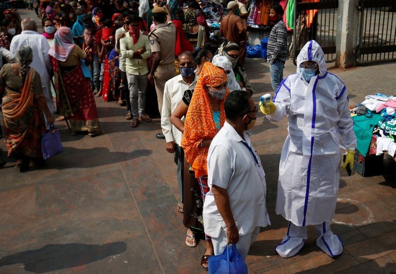 Healthcare worker wearing personal protective equipment (PPE) checks the temperature of shoppers outside a market, ahead of the Hindu festival of Diwali, amidst the spread of COVID-19 in Ahmedabad, India, November 12, 2020. (REUTERS Photo)