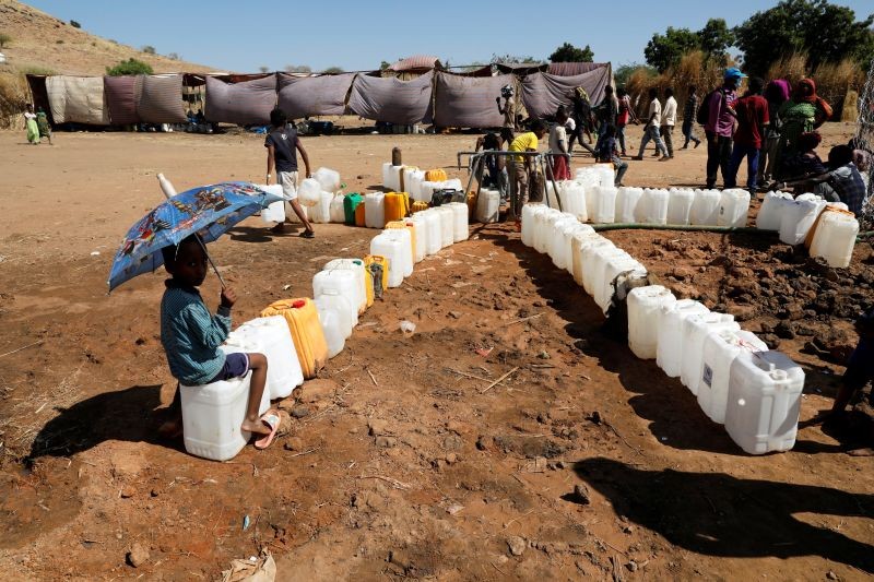 Ethiopian refugee child holds an umbrella as they sit in line for water, at the Um Rakuba refugee camp which houses refugees fleeing the fighting in the Tigray region, on the Sudan-Ethiopia border in Sudan, November 29, 2020. (REUTERS Photo)