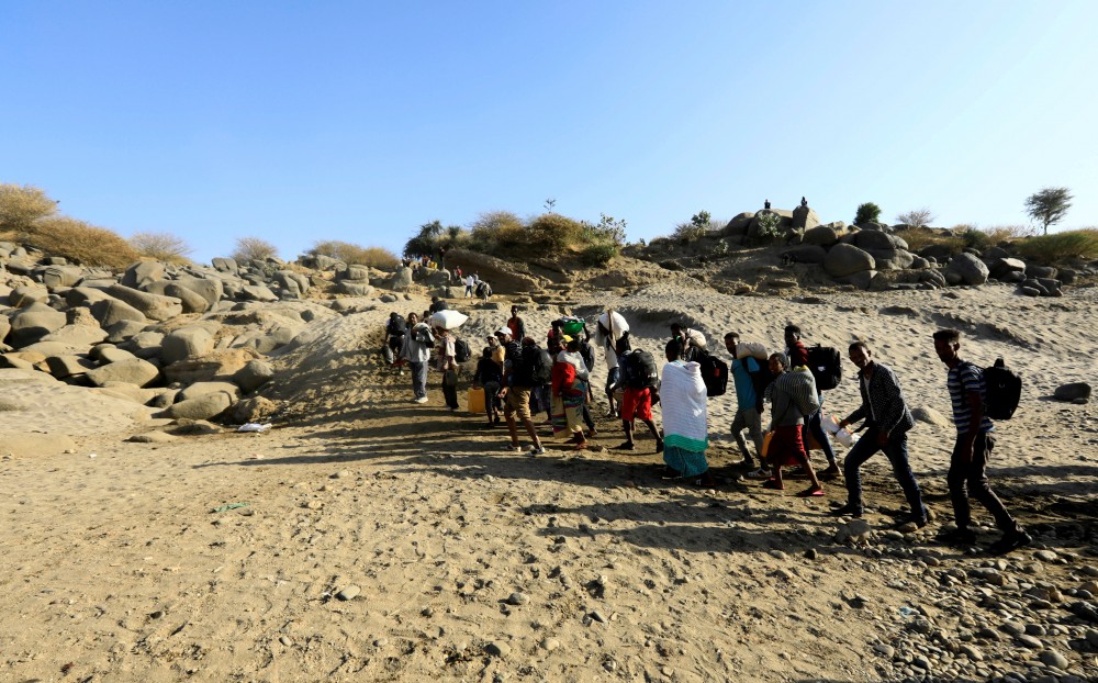 Ethiopians who fled the ongoing fighting in Tigray region, carry their belongings from a boat after crossing the Setit river on the Sudan-Ethiopia border in Hamdayet village in eastern Kassala state, Sudan November 22, 2020. REUTERS/Mohamed Nureldin Abdallah