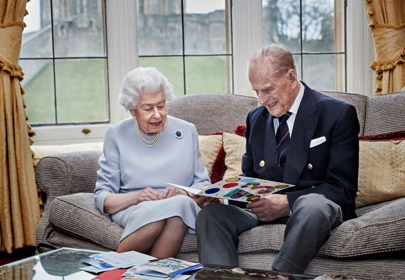 Britain's Queen Elizabeth and Prince Philip, Duke of Edinburgh look at their homemade wedding anniversary card, given to them by their great grandchildren Prince George, Princess Charlotte and Prince Louis, ahead of their 73rd wedding anniversary, in the Oak Room at Windsor Castle, Windsor, Britain November 17, 2020. Chris Jackson/Getty Images Europe/Handout via REUTERS