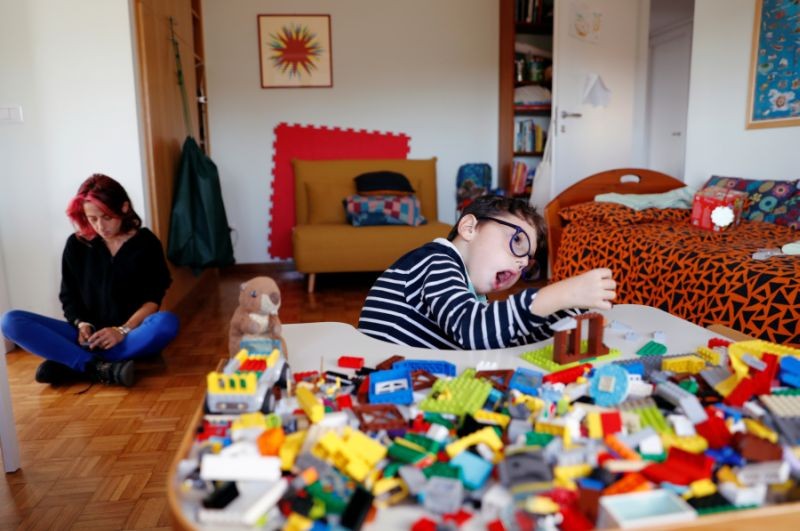 Sirio Persichetti, a 7-year-old Italian with spastic tetraplegia and cerebral palsy who has become an influencer by challenging perceptions of disability, builds a house out of lego, as his mum Valentina Perniciaro rests beside him, in Rome, Italy, October 20, 2020. (REUTERS File Photo)