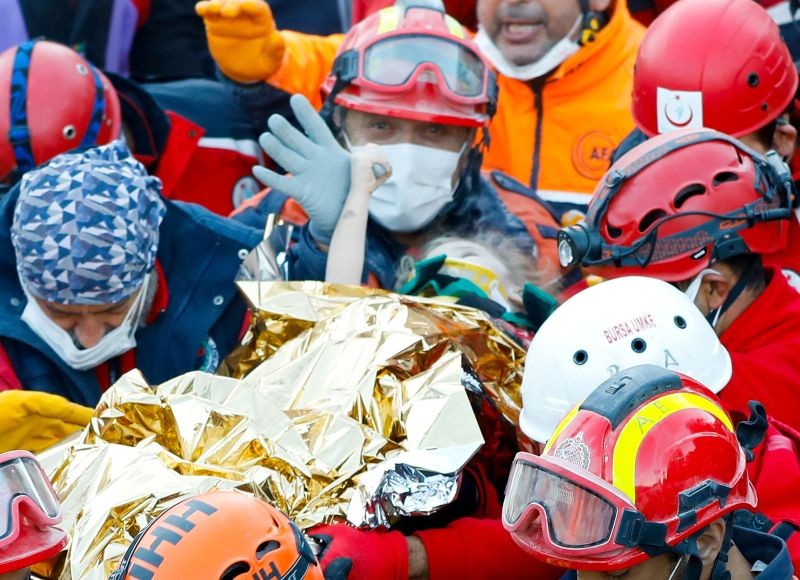 Elif Perincek, a three-year-old survivor, holds the thumb of a rescue worker as she is carried out of a collapsed building after an earthquake in the Aegean port city of Izmir, Turkey November 2, 2020. (REUTERS Photo)