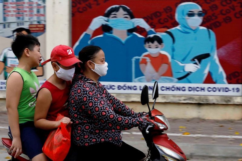 A woman wears a protective mask as she drives past a banner promoting prevention against the coronavirus disease (COVID-19) in Hanoi, Vietnam on July 31, 2020. (REUTERS File Photo)