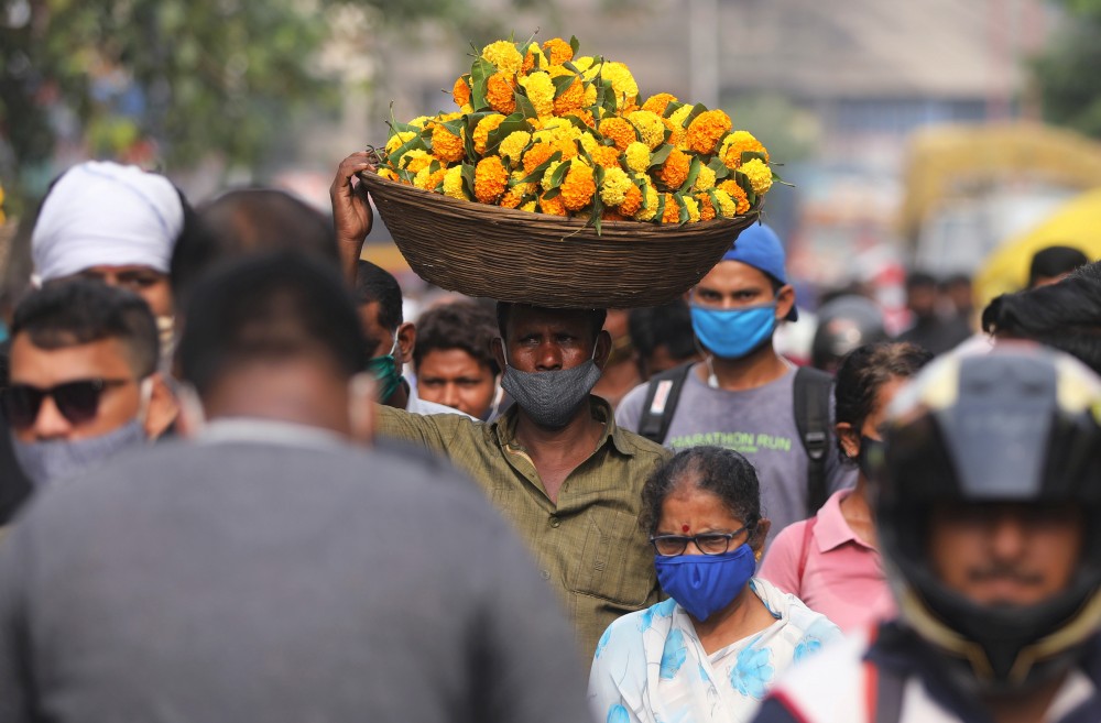 A man carrying flowers walks in a crowded market a day before the Hindu festival of Dussehra amidst the spread of the coronavirus disease (COVID-19) in Mumbai, India, October 24, 2020. REUTERS/Francis Mascarenhas
