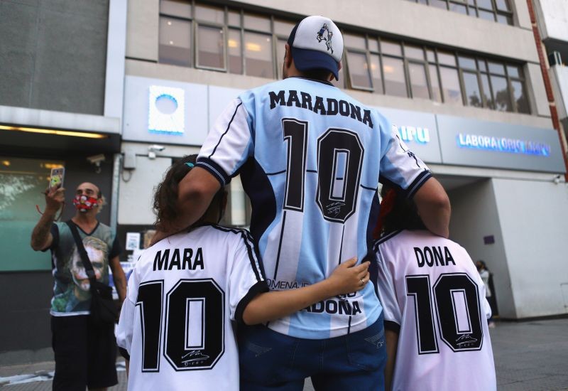 FILE PHOTO: Fans of Argentine soccer great Diego Maradona, Walter Rotundo and his twin daughters Mara and Dona, who are named after Maradona, pose for a photograph outside the clinic where Maradona underwent brain surgery, in Olivos, on the outskirts of Buenos Aires, Argentina November 5, 2020. REUTERS/Matias Baglietto