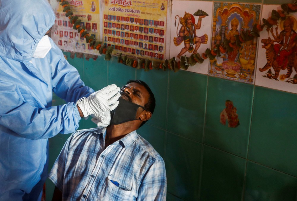 A health worker in personal protective equipment (PPE) collects a swab sample from a man during a rapid antigen testing campaign for the coronavirus disease (COVID-19), at a vegetable market in Mumbai, November 21, 2020. REUTERS/Francis Mascarenhas
