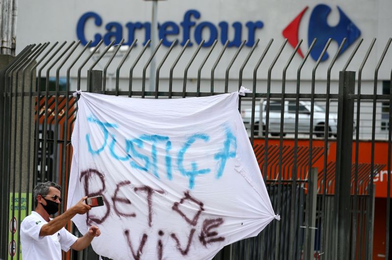 A man takes a picture next to a banner that's reads: "Justice. Beto lives", after Joao Alberto Silveira Freitas was beaten to death by security guards at a Carrefour supermarket in Poro Alegre, Brazil, November 20, 2020. (REUTERS Photo)