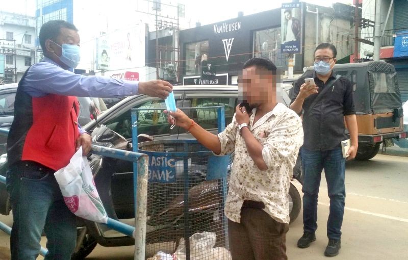 A Dobashi from the district administration handing out a mask to a pedestrian. (Morung Photo)