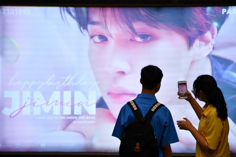 A woman takes a picture of a billboard whishing happy birthday to a K-pop singer Jimin at the subway in Bangkok, Thailand November 2, 2020. (REUTERS Photo)