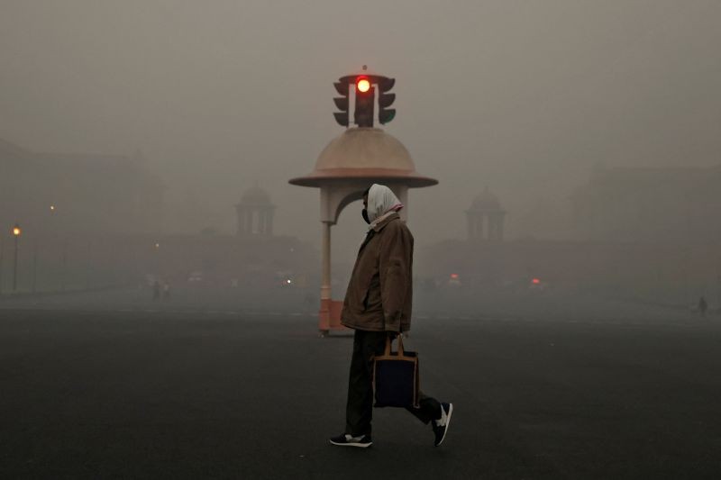 An office-goer walks past a traffic signal near various federal government ministries on a smoggy morning in New Delhi, India, November 10, 2020. (REUTERS Photo)