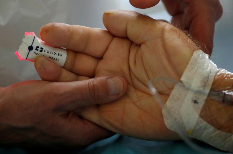 A physiotherapist holds the hand of a patient suffering from the coronavirus disease (COVID-19) in the Intensive Care Unit (ICU) at the hospital in Vannes during the outbreak of the coronavirus disease in France, November 12, 2020. (REUTERS Photo)