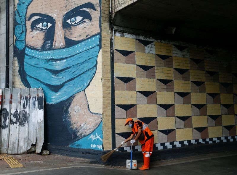 A worker wearing a protective face mask sweeps the street near a mural promoting awareness of the coronavirus disease (COVID-19) outbreak in Jakarta, Indonesia, October 2, 2020. (REUTER File Photo)