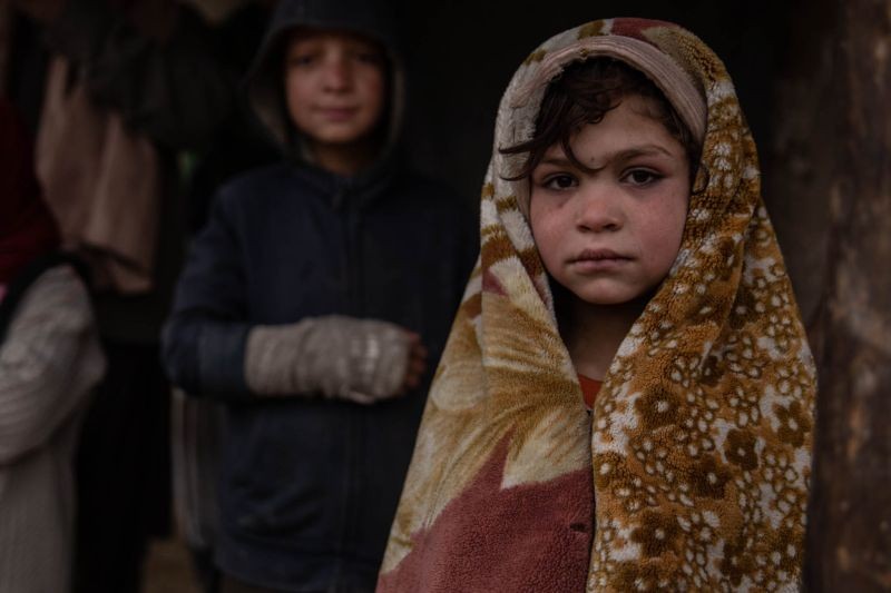 Fatima, 7, one of Azrat's eight children, is tying to stay warm in Kabul, 24 November 2020. (Thomson Reuters Foundation File Photo)