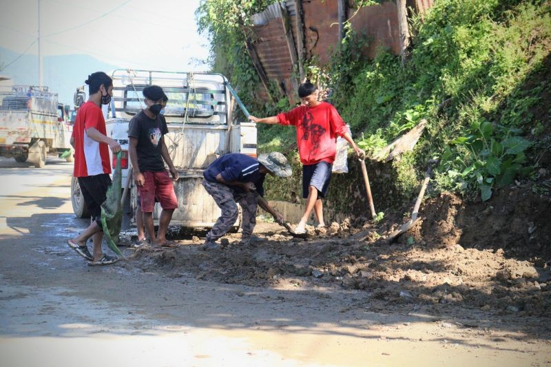 Members of The Gigglers and United Labours Society filling up a pothole with gravel and soil at High School Junction, Tuensang town on November 7. (Morung Photo)