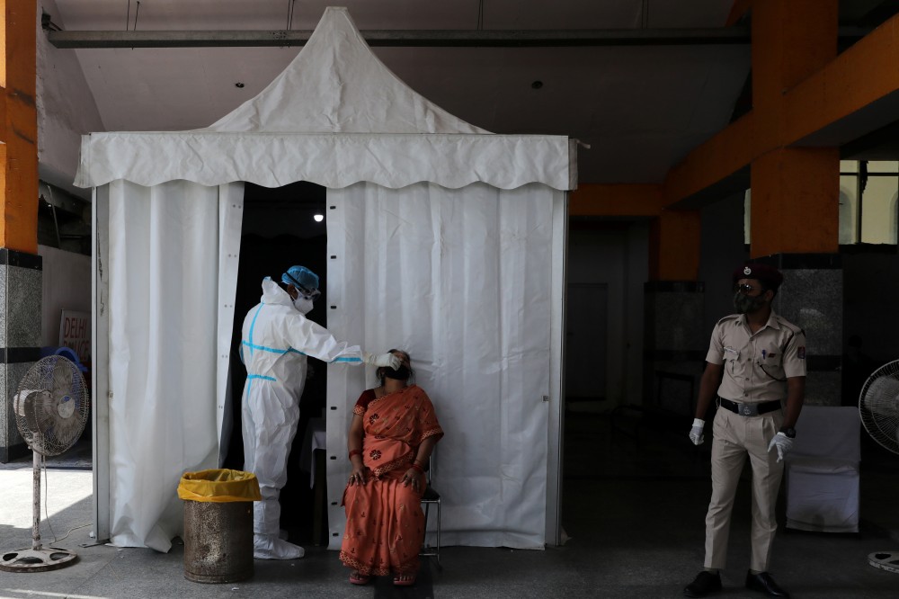 A healthcare worker wearing personal protective equipment (PPE) collects a swab sample from a woman, amid the spread of the coronavirus disease (COVID-19), in New Delhi, India, September 29, 2020. REUTERS/Anushree Fadnavis/Files