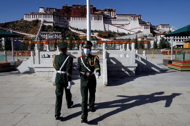 FILE PHOTO: Paramilitary police officers swap positions during a change of guard in front of Potala Palace in Lhasa, during a government-organised tour of the Tibet Autonomous Region, China, October 15, 2020. Picture taken October 15, 2020. REUTERS/Thomas Peter/File Photo