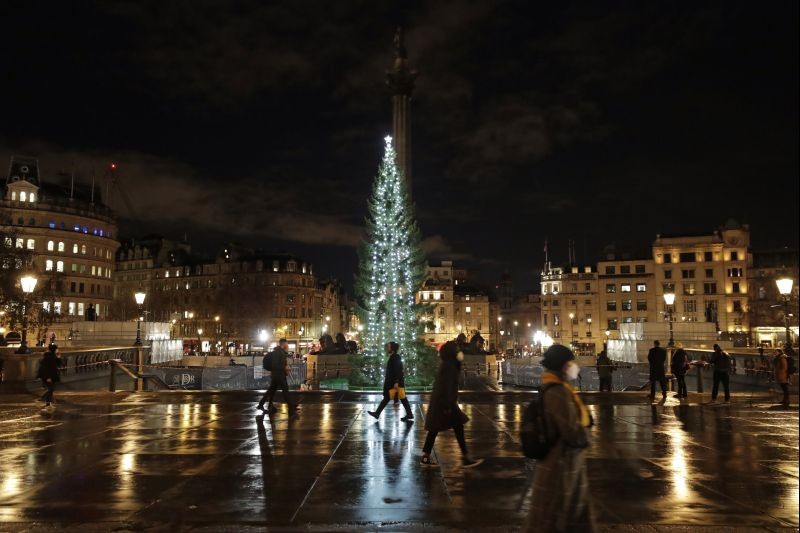 London:People wearing face masks walk past the illuminated Norwegian Christmas tree, after its lights were turned on without the usual ceremony to stop people gathering to try to curb the spread of coronavirus, in Trafalgar Square, London, Thursday, Dec. 3, 2020. AP/PTI Photo